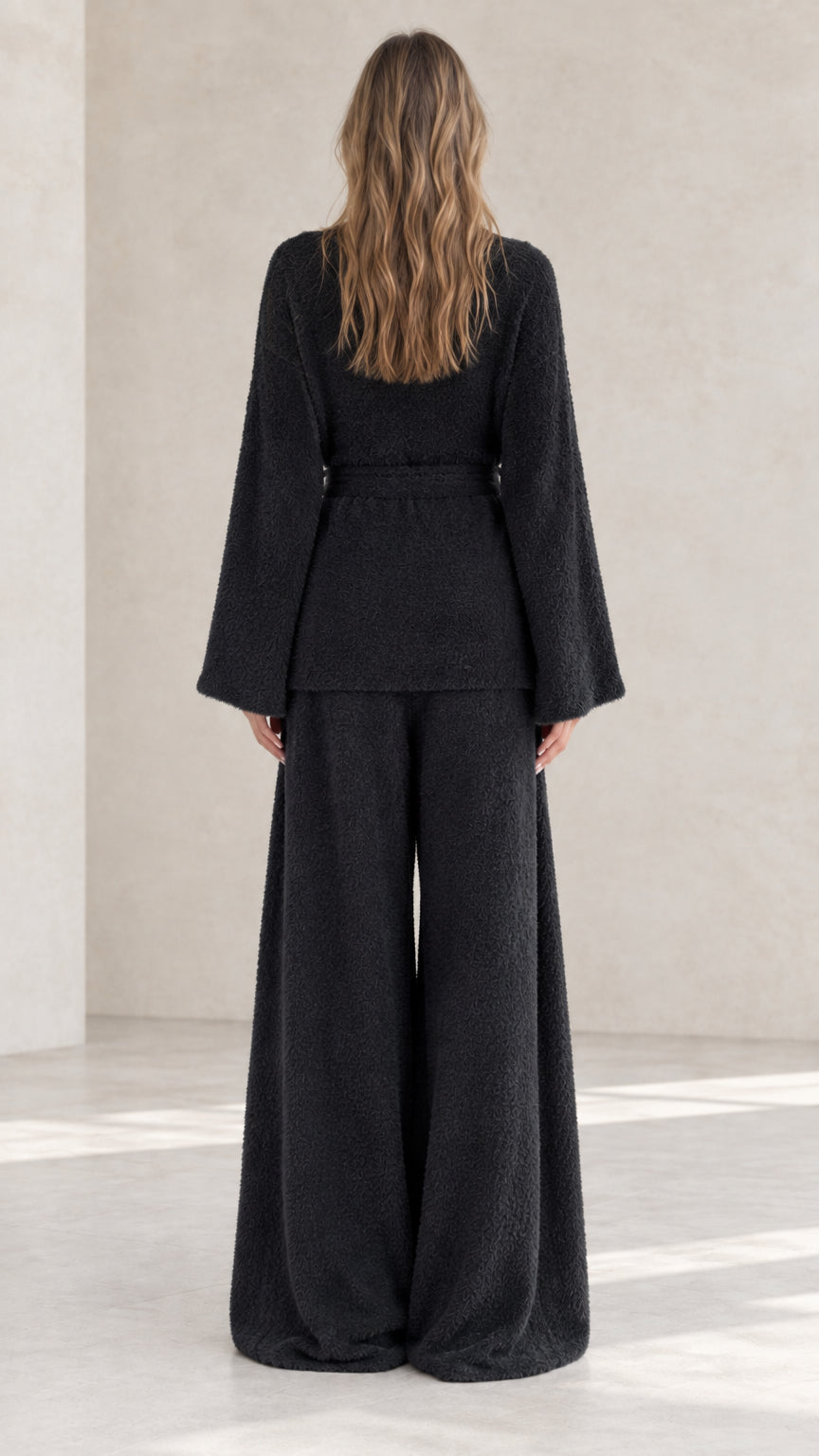 Black plush knit lounge set back view showing drape of wide leg pants