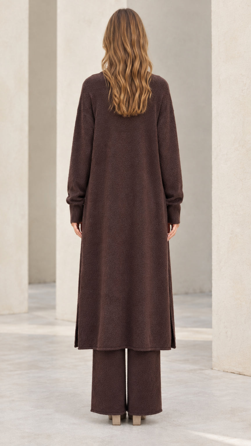Back full-length view of model wearing chocolate brown longline knit cardigan and wide leg pants