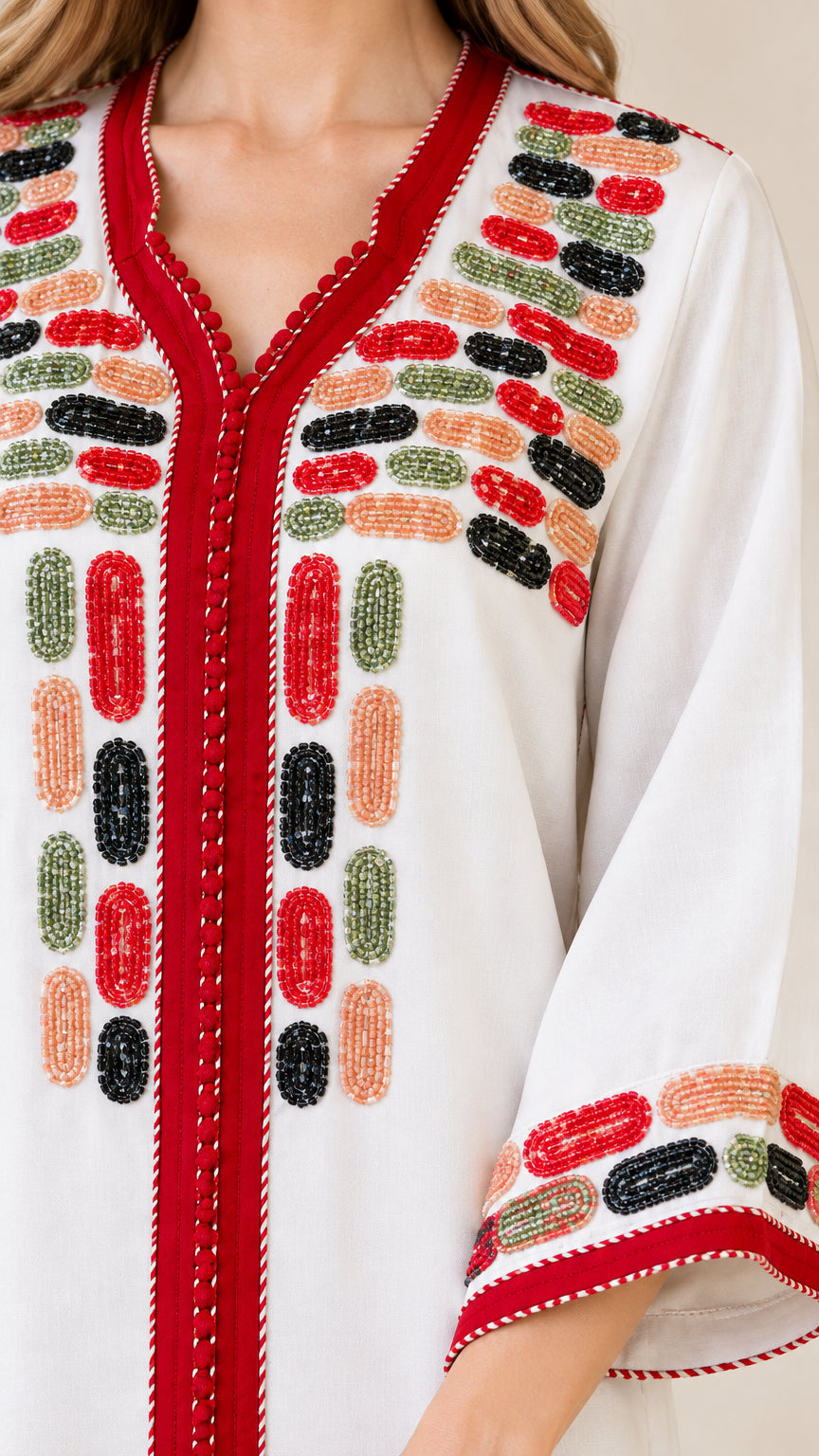 Close-up detail of geometric multi-color embroidery and red placket trim on kaftan dress