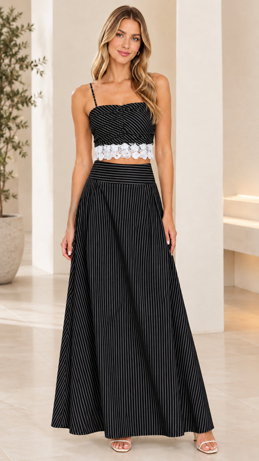 Front view of model wearing black and white striped crop top and maxi skirt set
