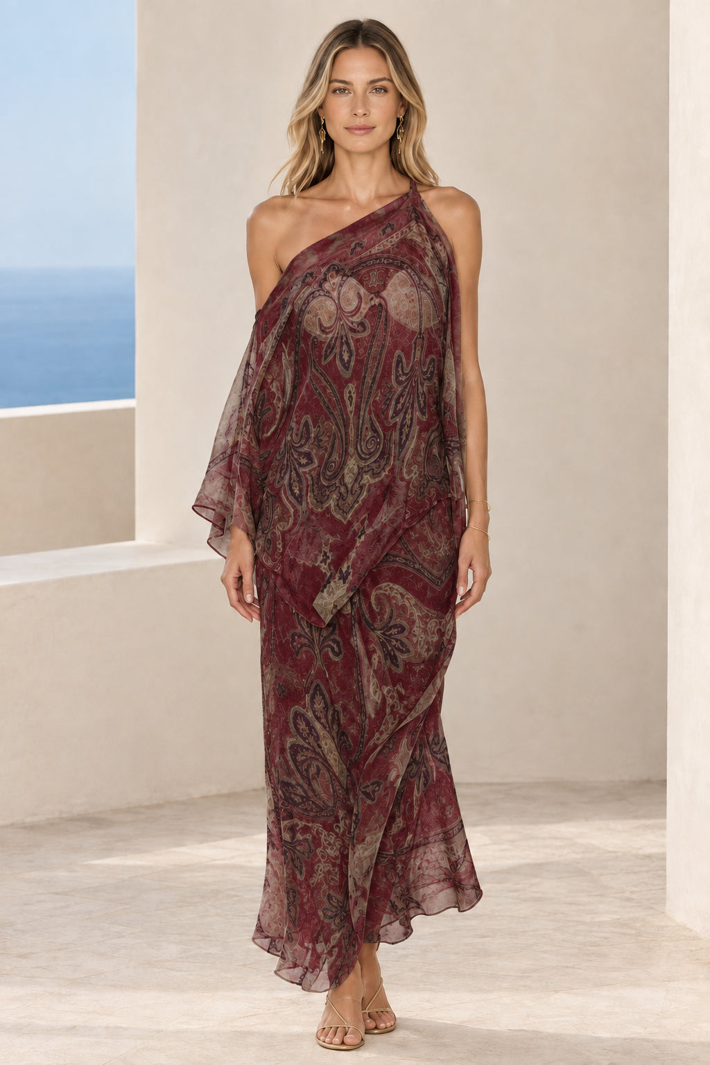 Front view of woman wearing burgundy wine red paisley print one-shoulder draped maxi dress