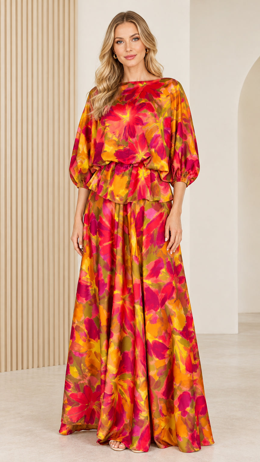 Front full view of woman wearing orange and magenta floral satin boat neck maxi dress