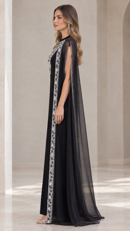 Side profile view of black floor-length cape maxi dress showing arm slit details
