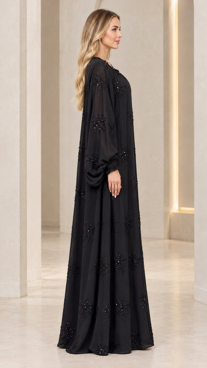 Side profile view of model in black long sleeve beaded kaftan maxi dress