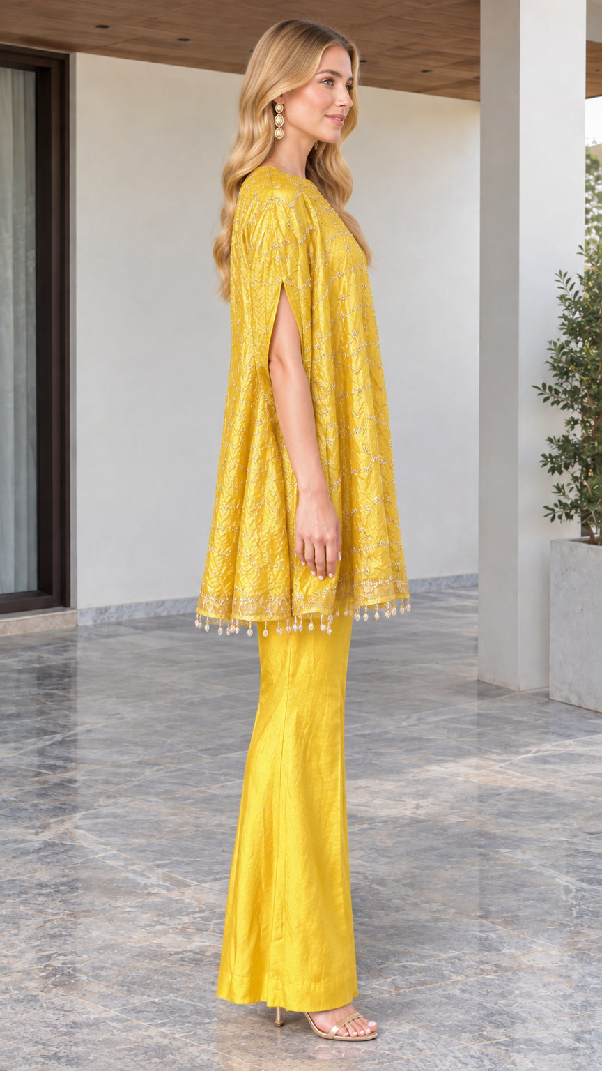 Side angle of model wearing yellow cape tunic top and matching wide leg pants