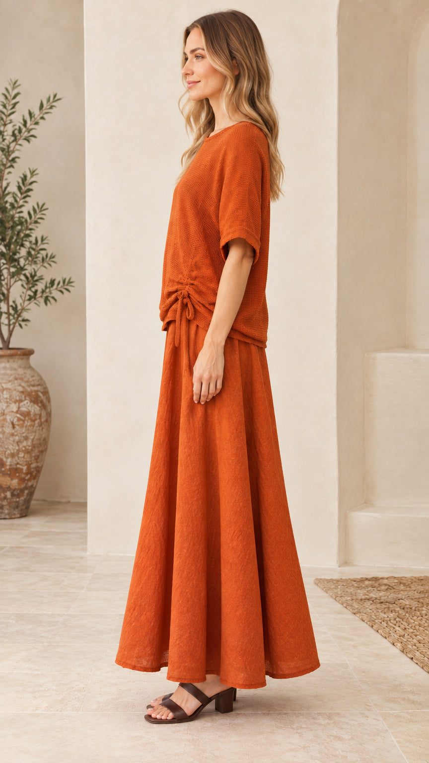 Side profile view of woman wearing rust textured two-piece top and maxi skirt set