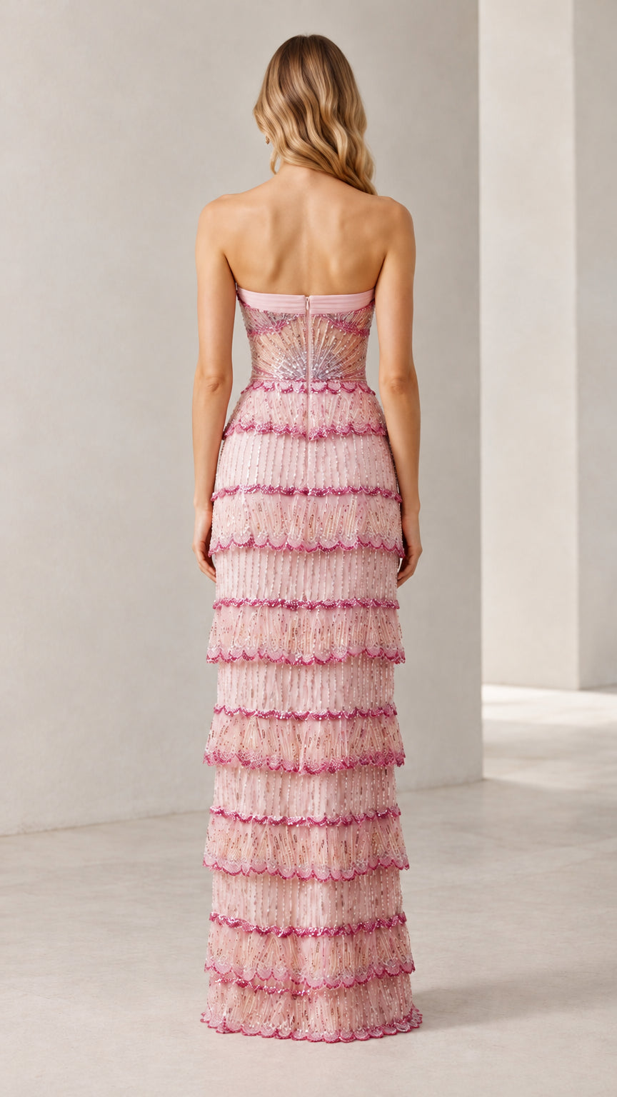 Back view of woman wearing strapless blush pink tiered evening dress