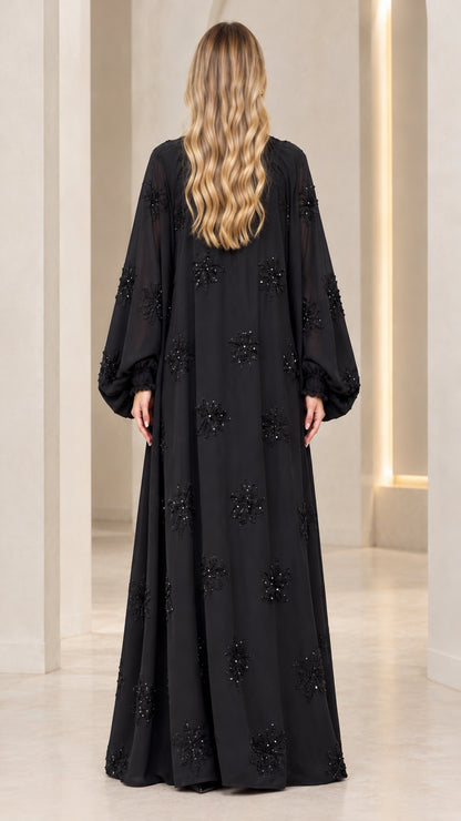 Back full-length view of black beaded flowy evening maxi dress