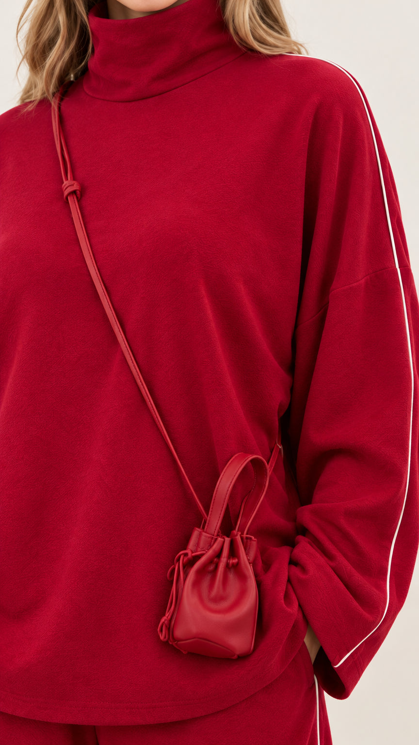 Close-up detail of red mock neck top with delicate white piping along the sleeve