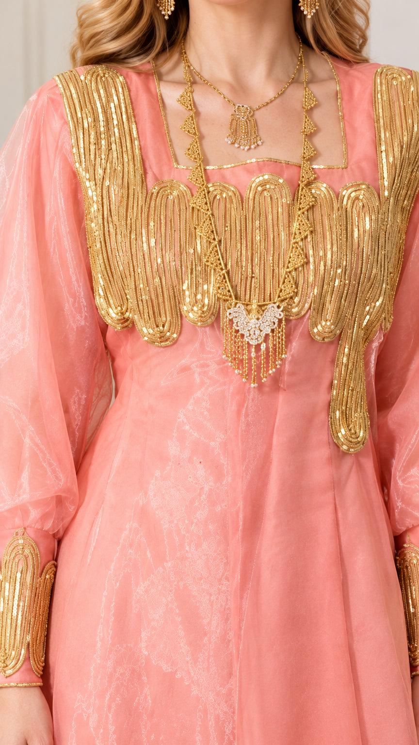Close-up detail of ornate gold metallic embroidery and yoke embellishment on pink dress