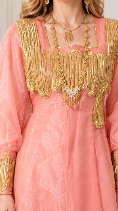 Close-up detail of ornate gold metallic embroidery and yoke embellishment on pink dress