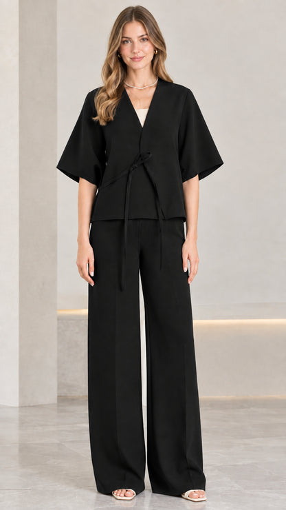 Front view of woman wearing black tie-front short sleeve top and wide-leg pants set