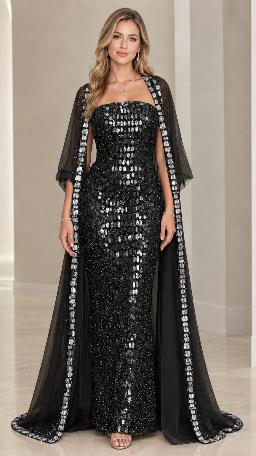 Black strapless embellished evening gown paired with sheer black trimmed cape