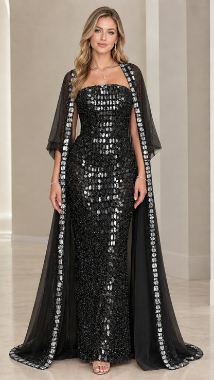 Black strapless embellished evening gown paired with sheer black trimmed cape