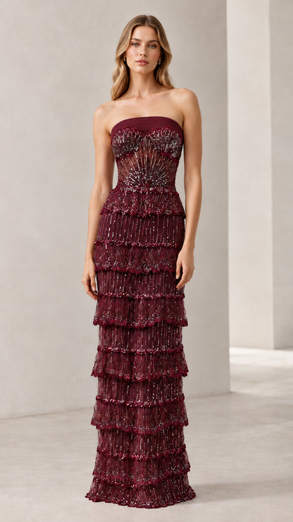 Full-length view of woman wearing burgundy strapless beaded tiered evening gown