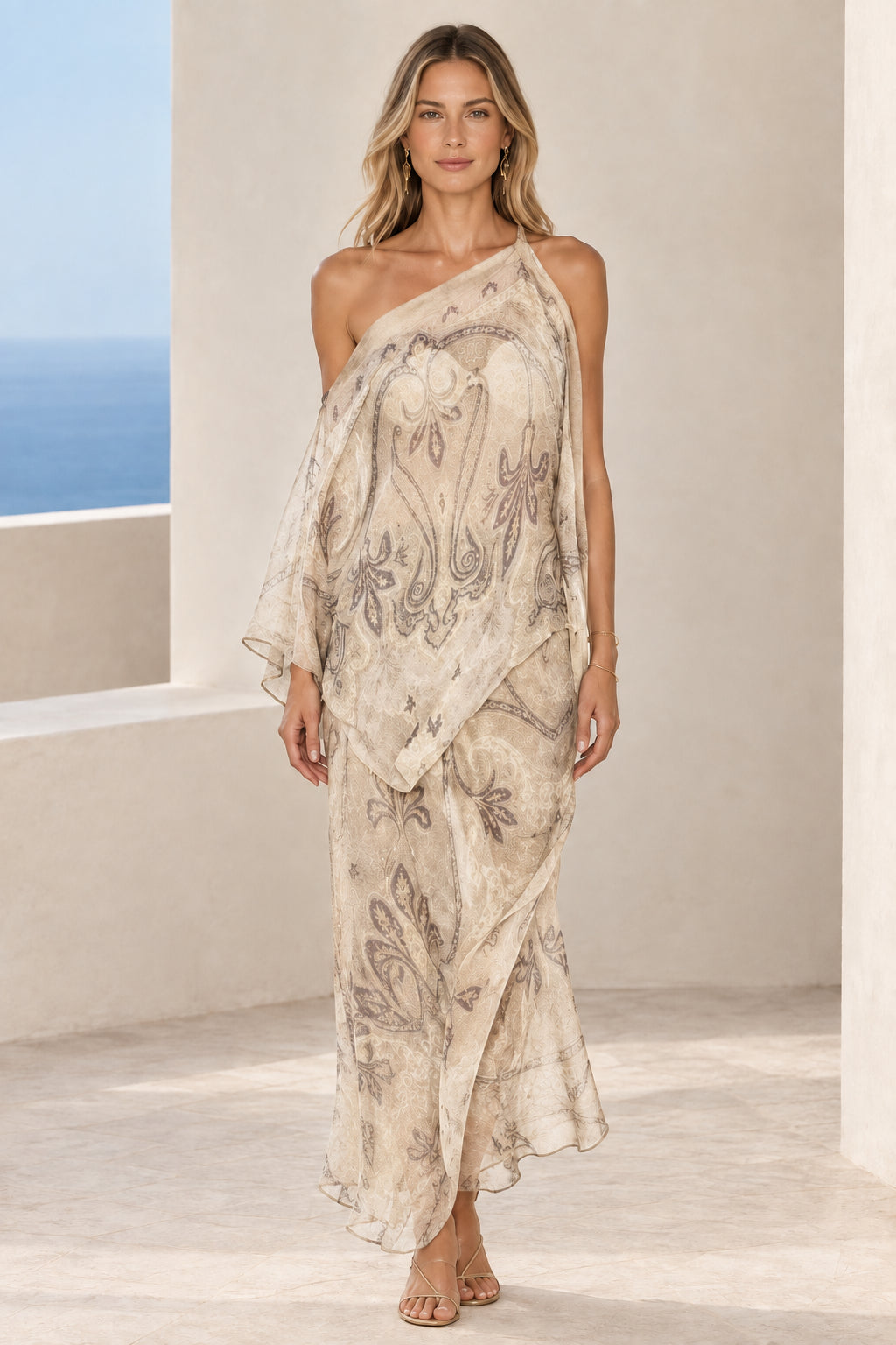 Front view of woman wearing cream ivory paisley print one-shoulder draped maxi dress
